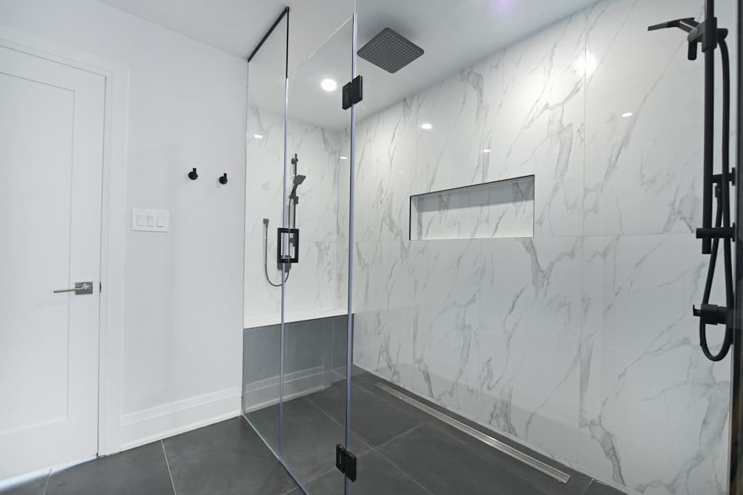 Inloopdouche met glaswand en grote tegels in een moderne badkamer