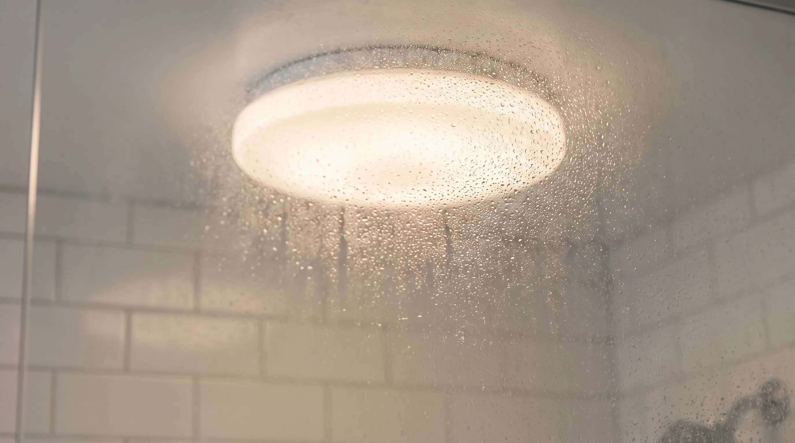 Afgesloten plafondlamp met waterdruppels in een douchezone