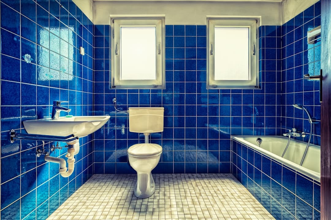 Retro badkamer met glanzende blauwe wandtegels en een mozaïekvloer