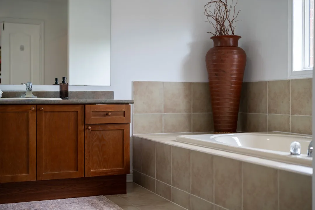Warme badkamer met een bruin houten wastafelmeubel en een ingebouwd bad in beige tegels