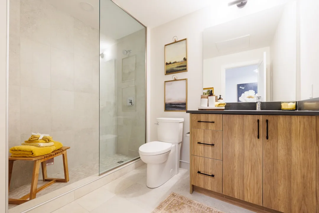 Lichte badkamer met een licht houten wastafelmeubel en een houten bankje in de inloopdouche