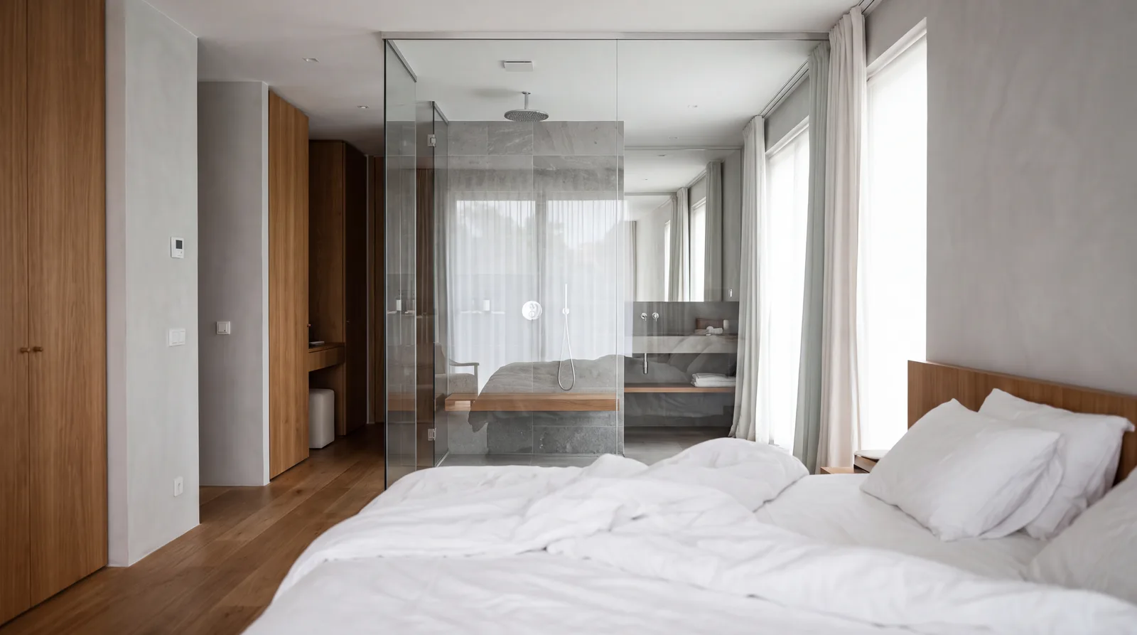 Glazen wand tussen de inloopdouche en de slaapkamer, met een bed op de voorgrond